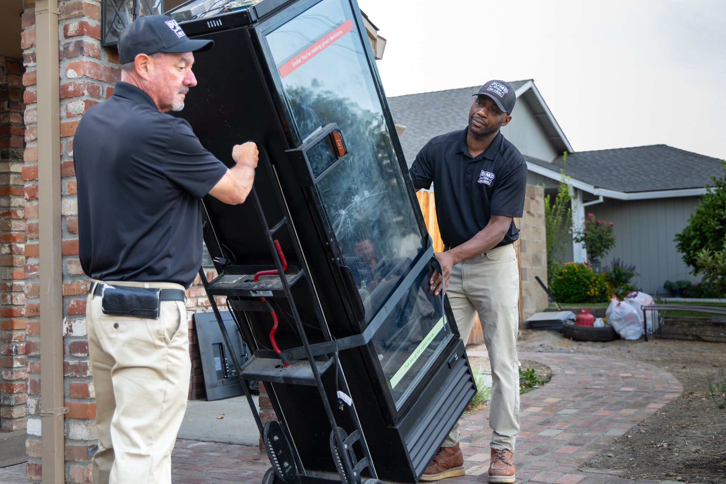 Dump Ninja crew member moving an old appliance on a hand truck during a garage cleanout in West Sacramento, CA
