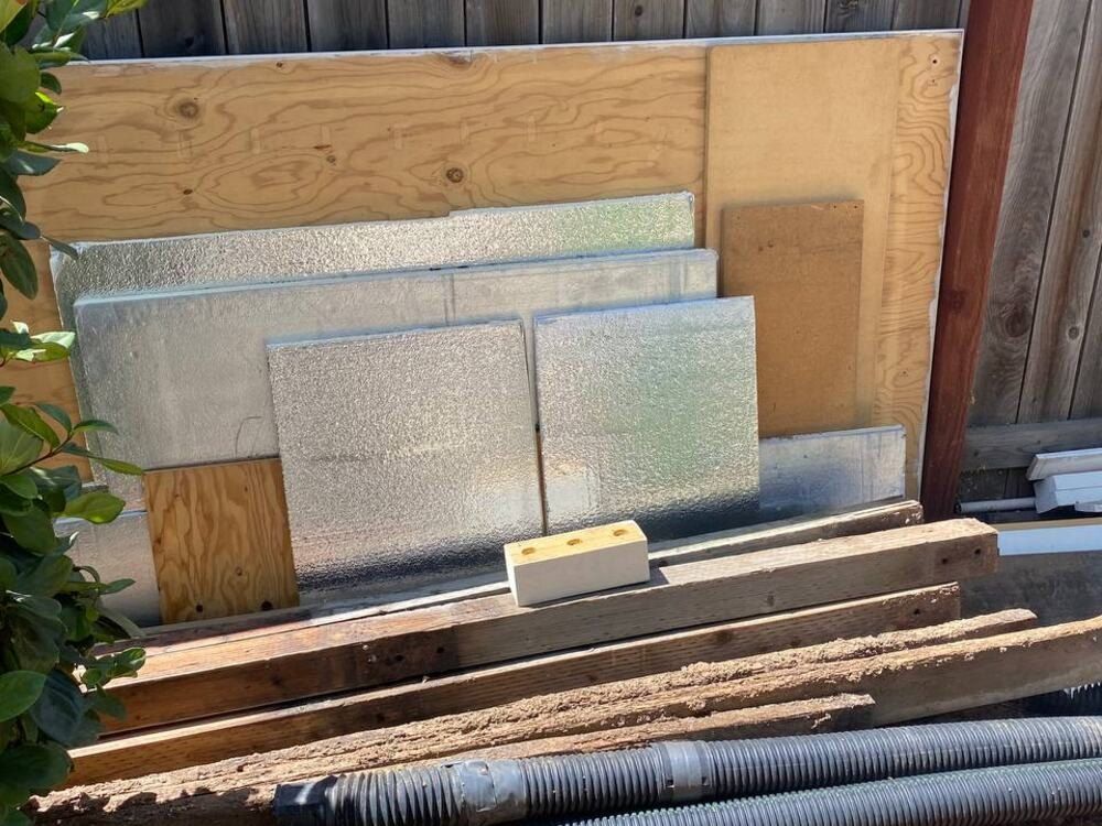 Before: sheets of plywood stacked along a backyard fence