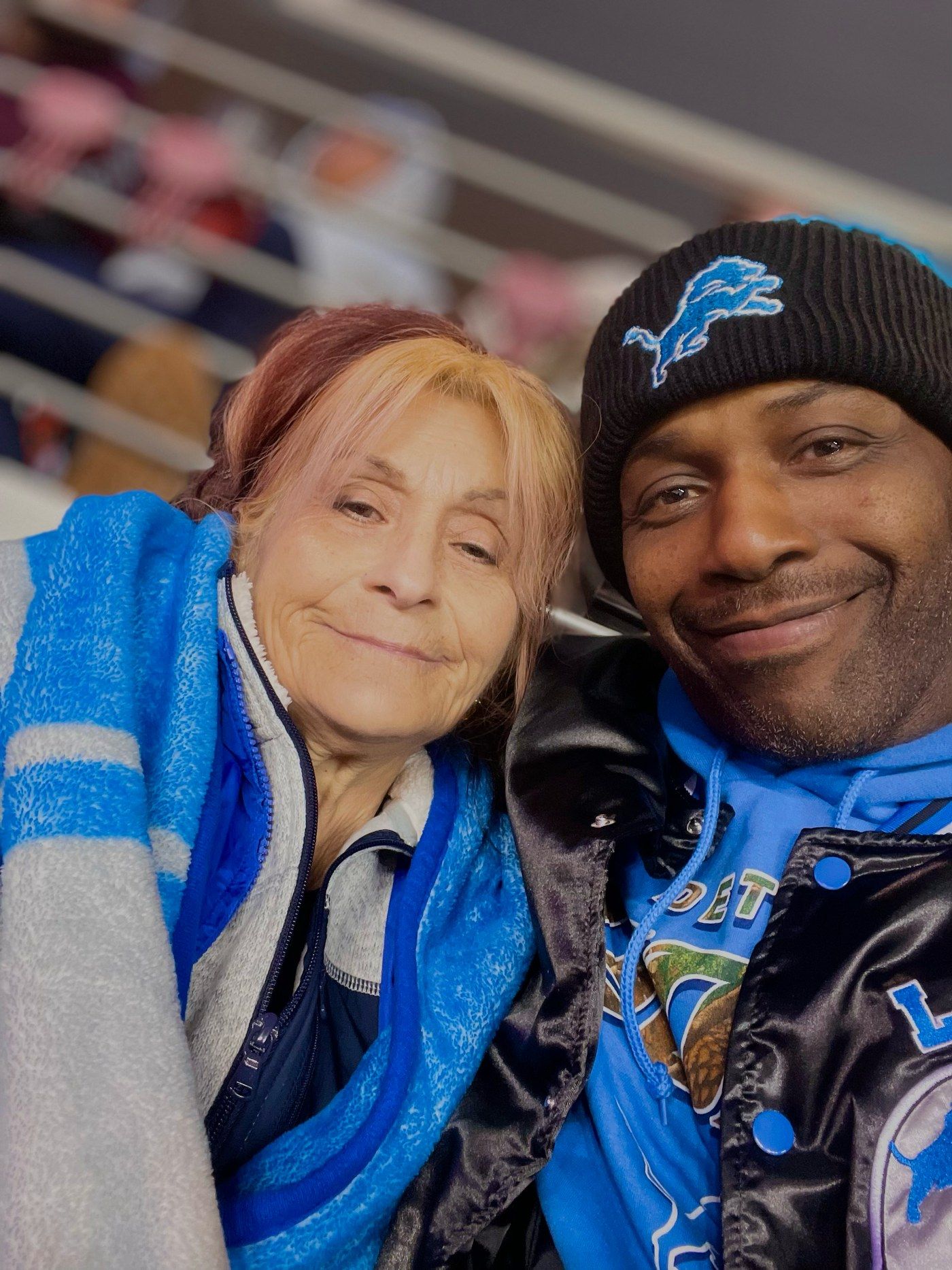 Fabian Harris on the right, wearing Detroit Lions gear, with a companion in the stadium stands