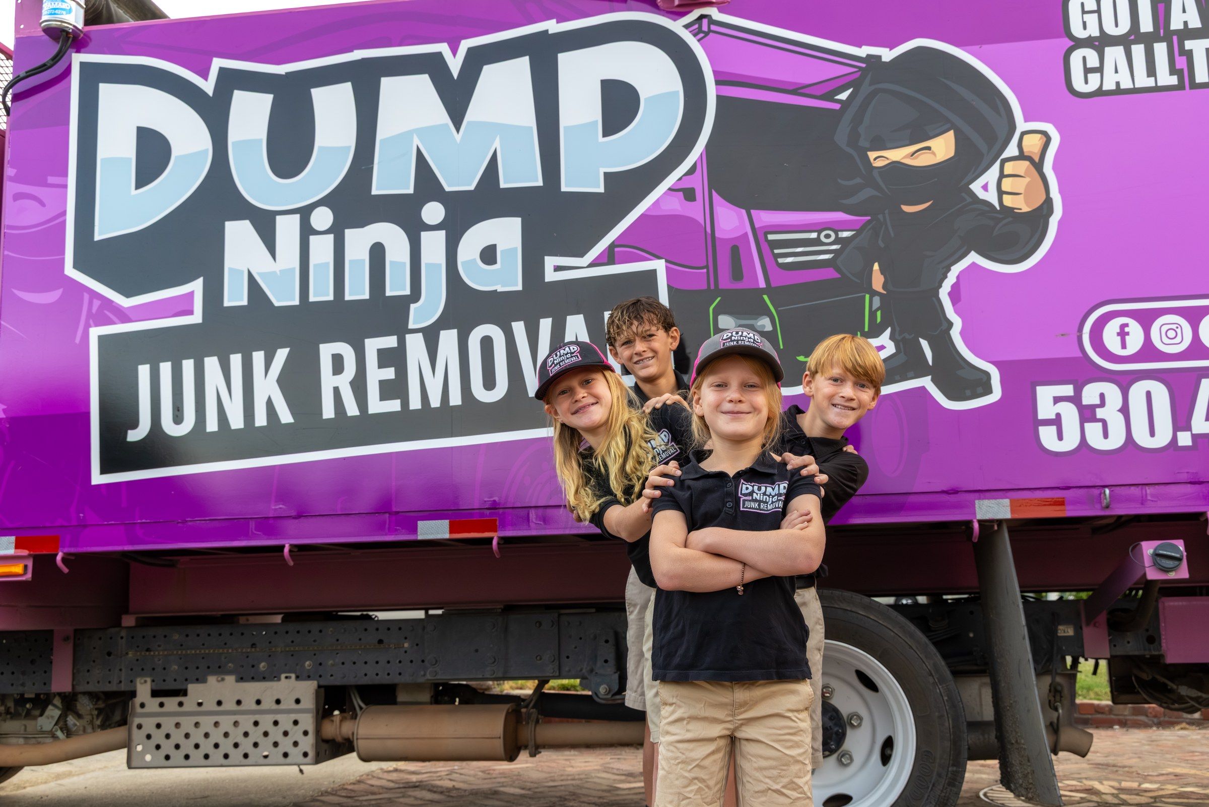 Jeremy Mahan with his wife and four kids in Dump Ninja uniforms beside the magenta truck
