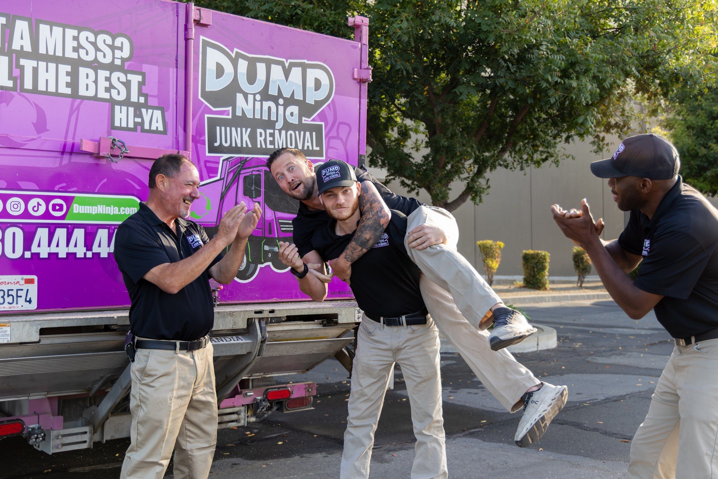 The Dump Ninja crew sitting on the tailgate of the magenta 21-yard truck
