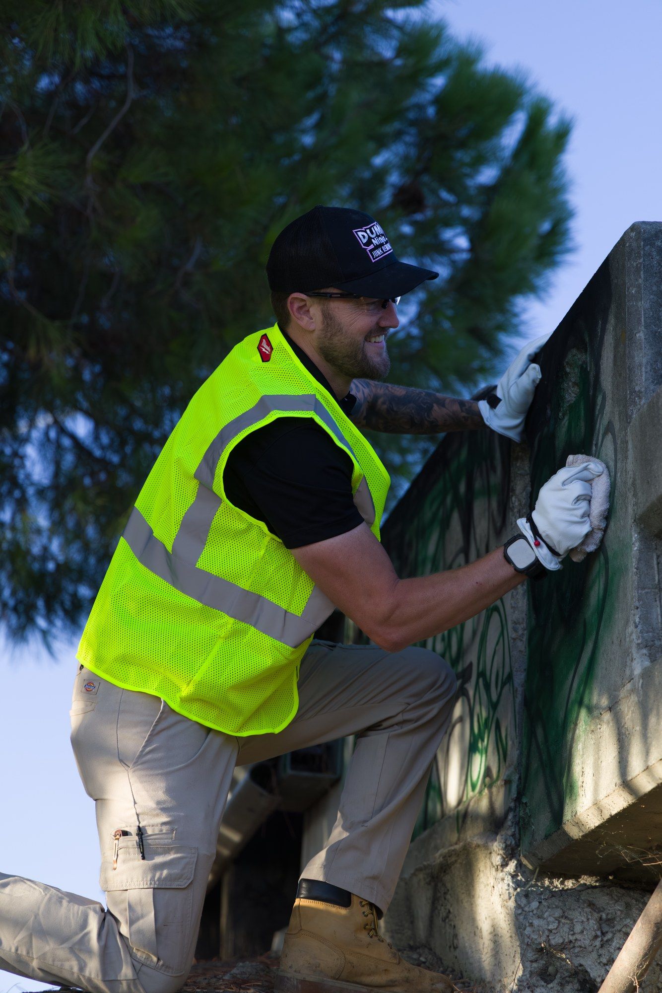 Close-up of a Dump Ninja crew member removing graffiti from a concrete wall on commercial property