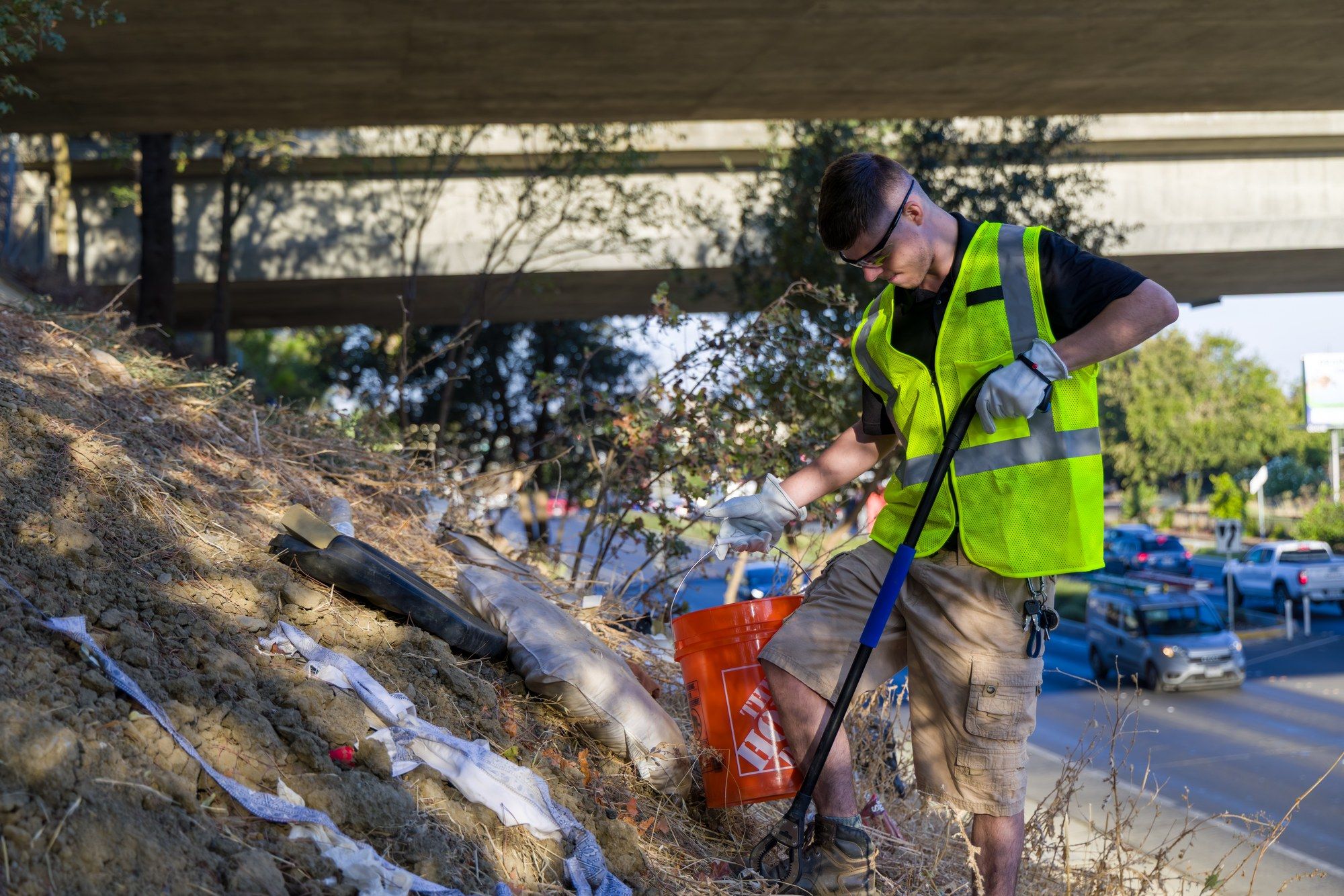 Two Dump Ninja crew members clearing encampment debris from under an overpass in Yolo County