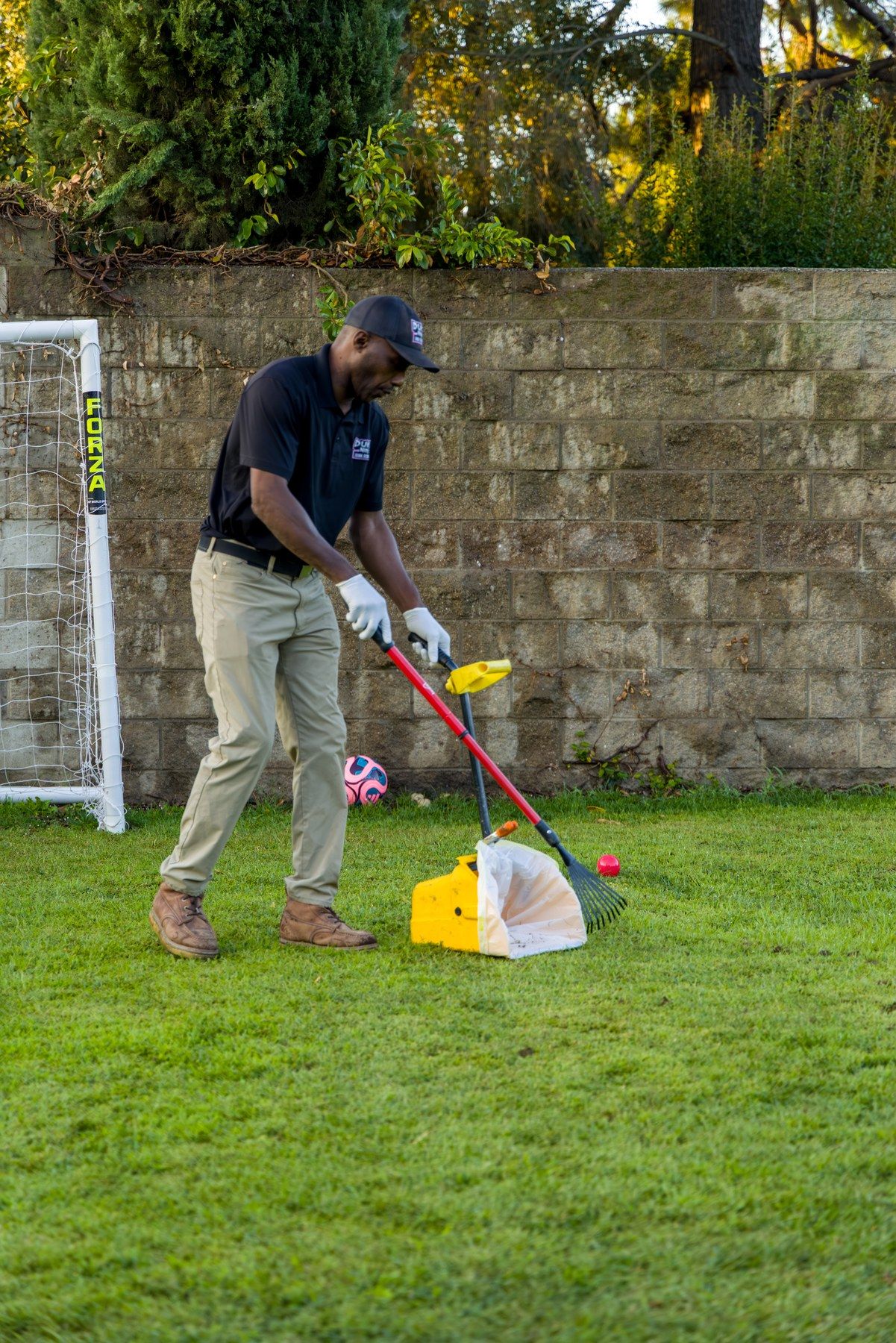 Dump Ninja crew member scooping along a brick wall on a shared property in Woodland