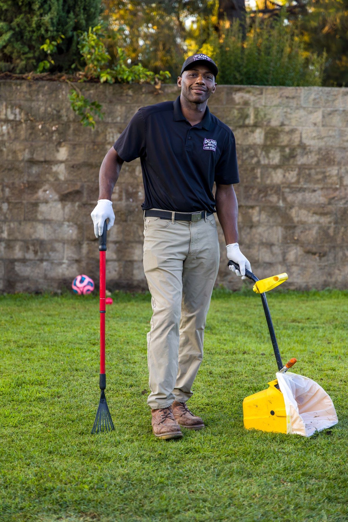 Dump Ninja crew member standing with pet waste tools in front of a brick wall in Woodland