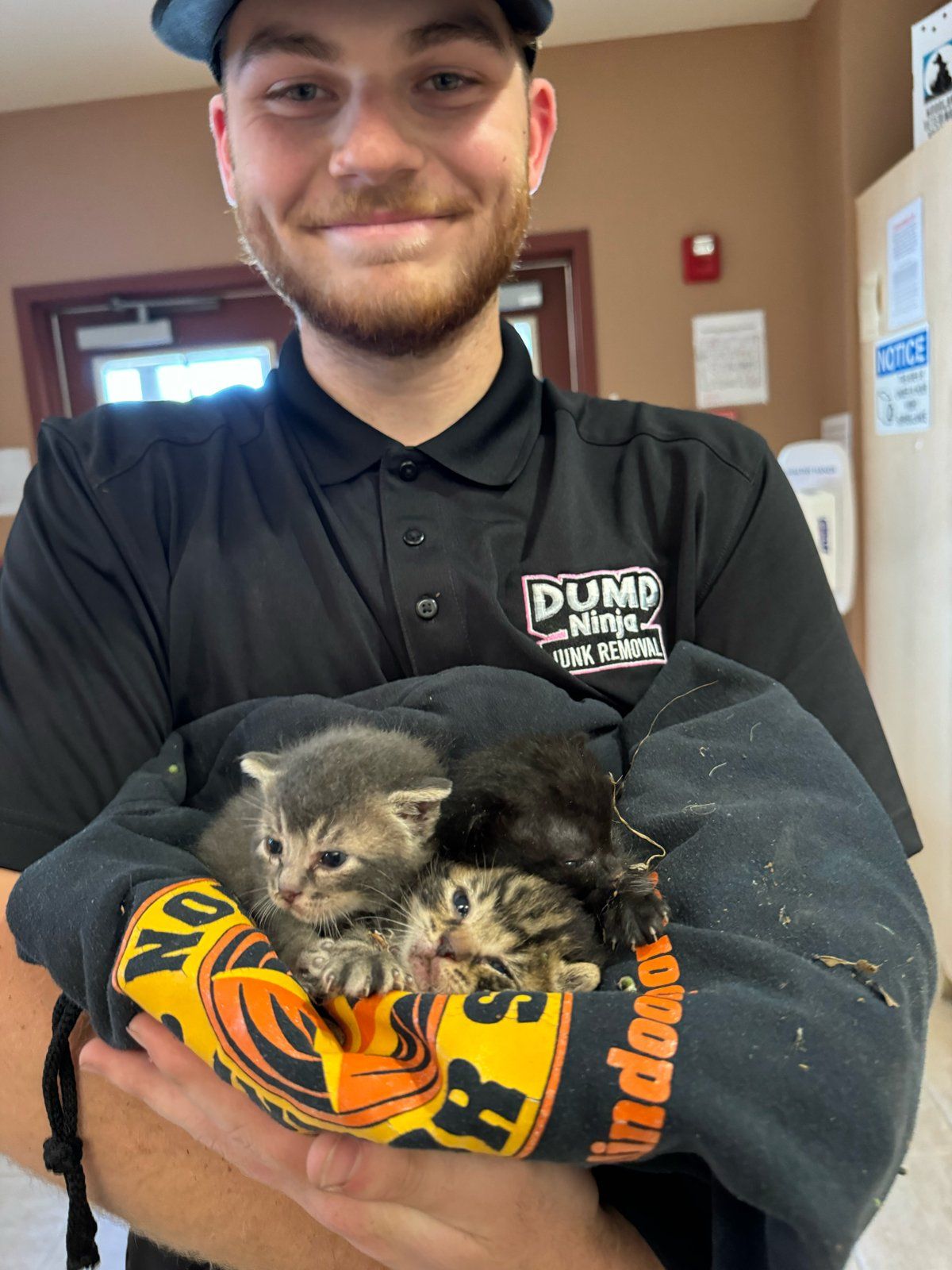 Roman Audiffred wearing his Dump Ninja shirt and holding kittens wrapped in a sweatshirt